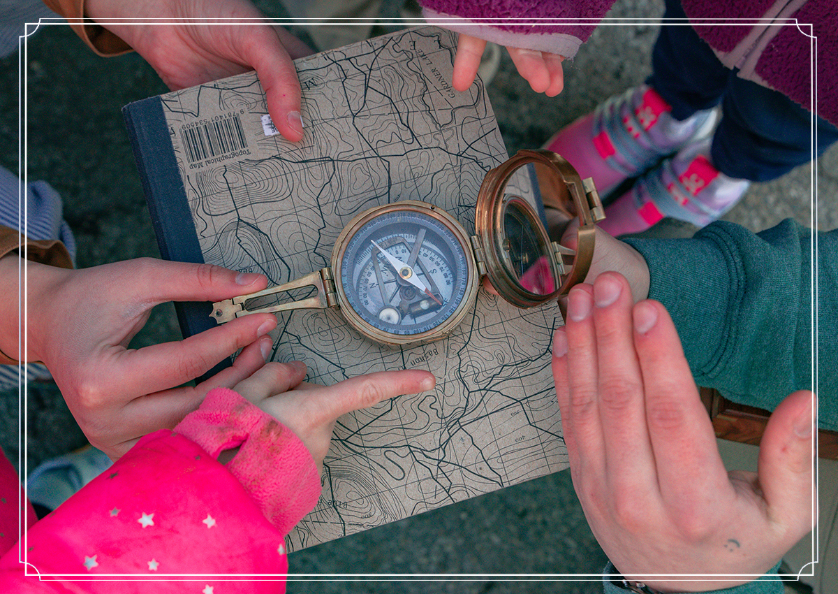 Close up of adults' and childrens' hands pointing to a compass