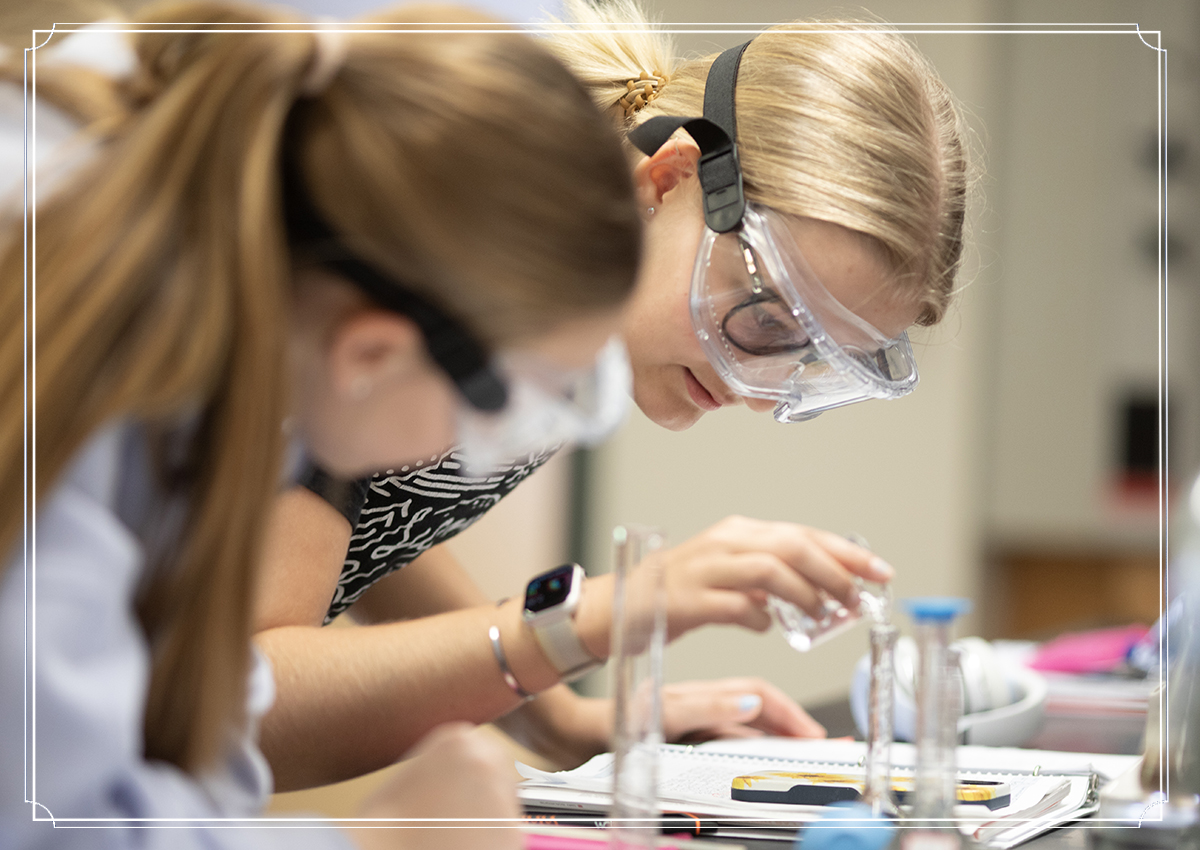 Two students with goggles in chemistry lab