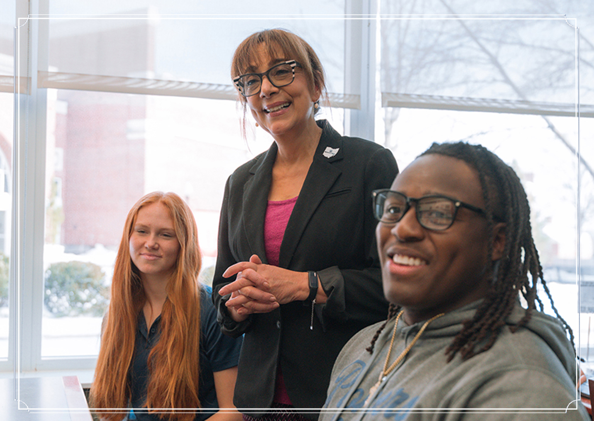 Professor stands next to two seated students in student success center