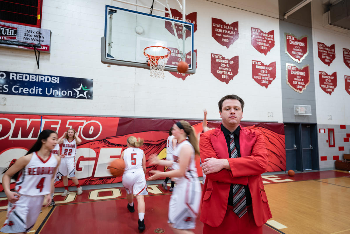 Tyler Bates '13 poses for a portrait as his basketball team runs drills behind him
