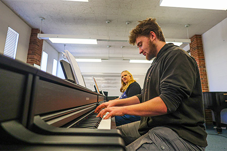 Music teacher and student at pianos in class