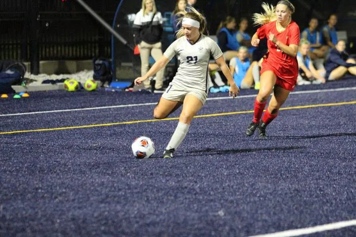 Women's soccer player kicking the ball