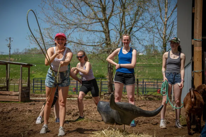 Students practice roping a fake cow