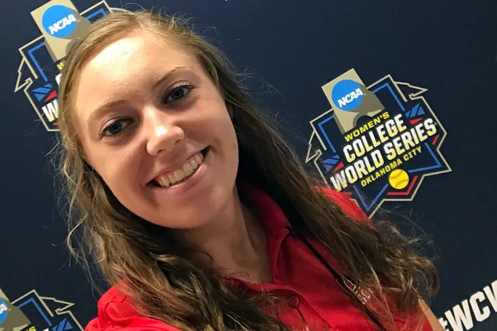 Micaela Bradley posing in front of Women's College World Series banner