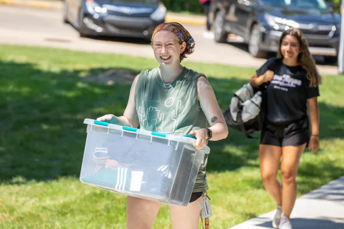 Female student carrying a plastic tub