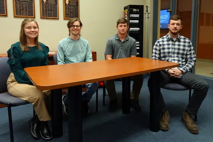 Four students sitting behind a table