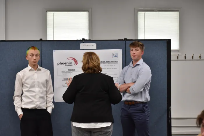 Two students speaking with a Junior PioBiz judge