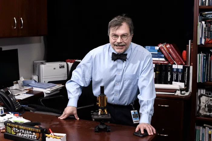 Peter Hotez standing behind his desk