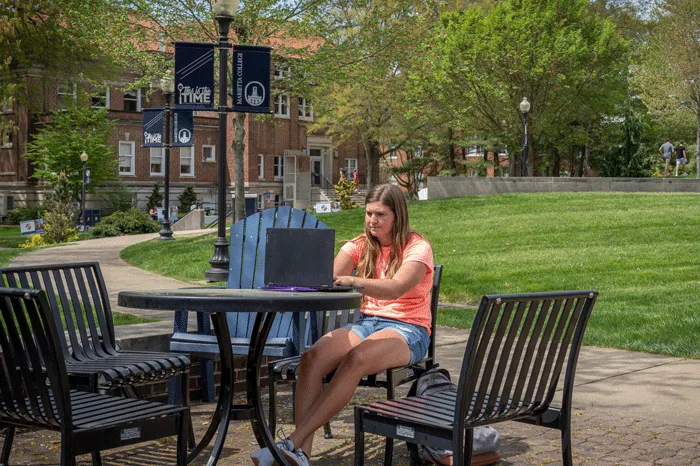 Student seated outside working on her laptop