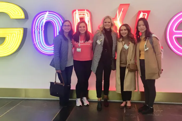 Group photo of students and faculty member in front of Google sign