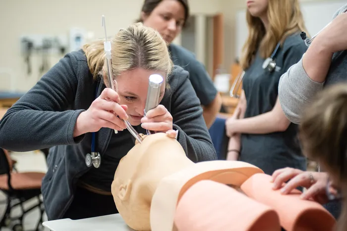 Female student learning to intubate a person