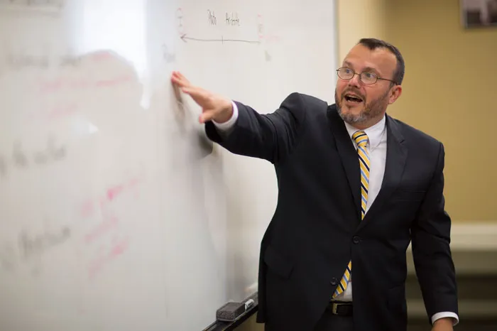 Gama Perruci teaching at a white board