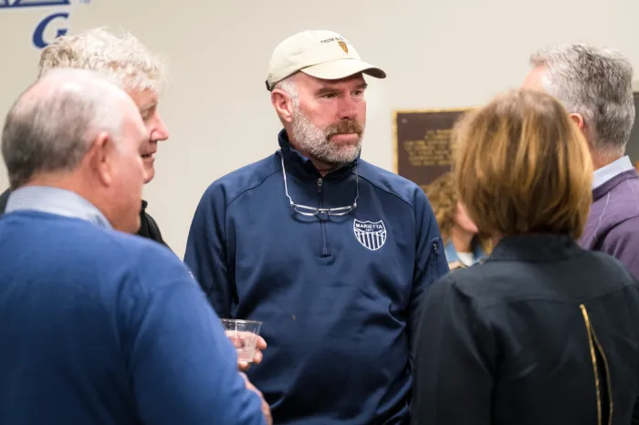 Alumnus Jeff Hugel speaks with other alumni at the boathouse