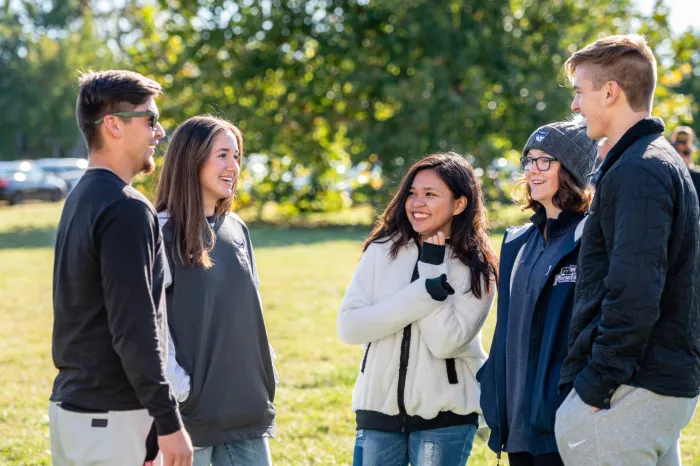 Harrison Scholars - Gabe Brunck, Emi Reindle, Hanna Jamelo, Anna Frost and Artemii Stepanets - chat during halftime of a football game.