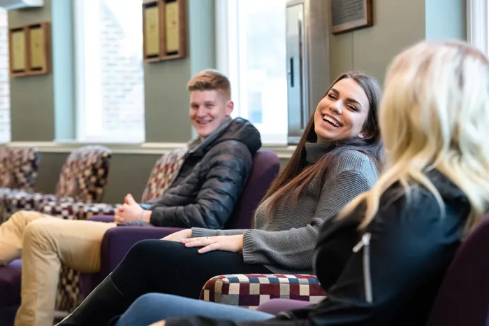 Female student smiling in between a male student on left and blonde female on right