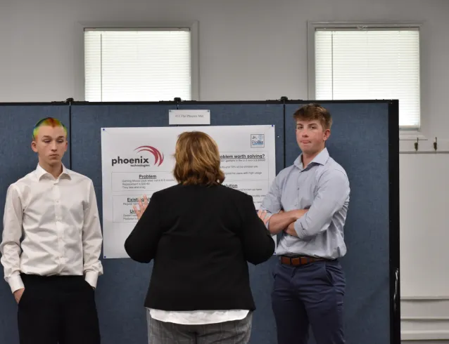 Two students speaking with a Junior PioBiz judge