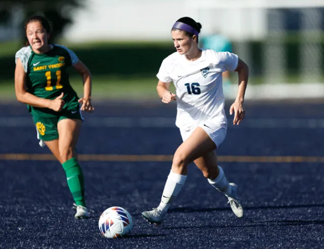 Women's soccer player runs away from a defender