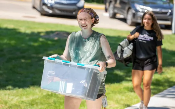 Female student carrying a plastic tub