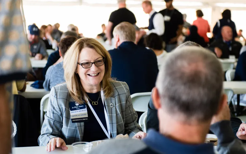 An alumnae sits and chats at the homecoming tailgate event