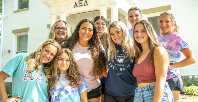 Alpha Xi Delta members standing in front of the renovated sorority house.