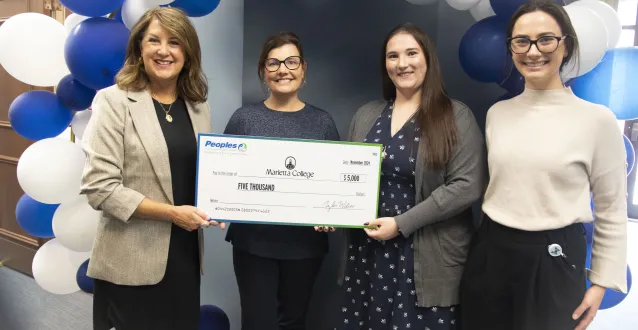 Peoples Bank representatives Staci Matheney and Tori Tadlock present Dr. Amy Elliott and Shannan Tschopp a $5,000 check