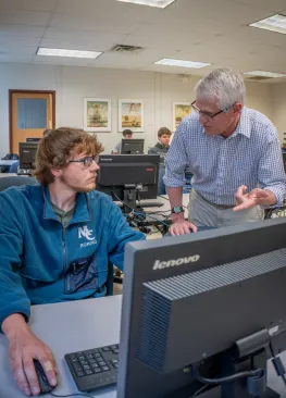 A Computer Science major works at a computer with Professor Bob Van Camp