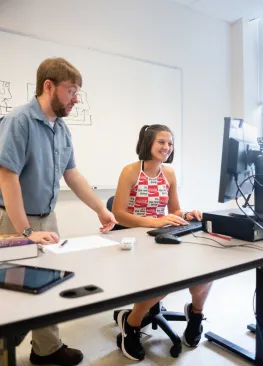 A Marietta College student majoring in information systems works with Professor Matt Williamson at a computer 