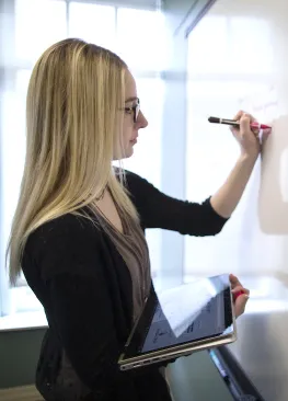 A Marietta College Student writes at a whiteboard.